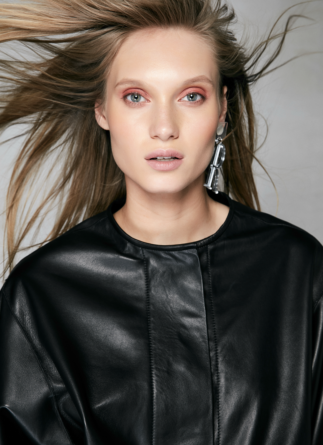Retrato femenino frontal con pelo en movimiento y chaqueta negra